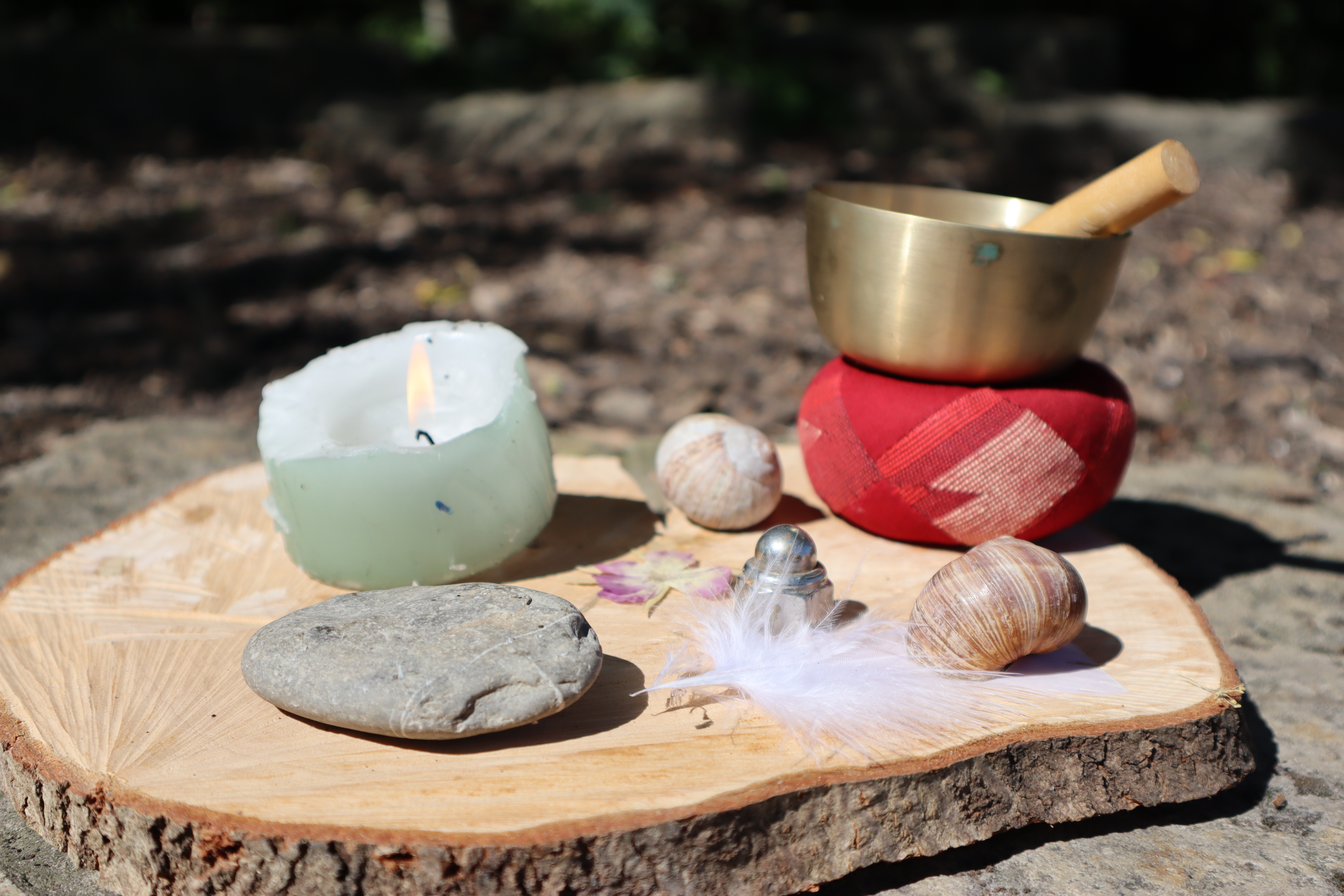 Steine, Kerze und Klangsschale auf einem Stück Holz