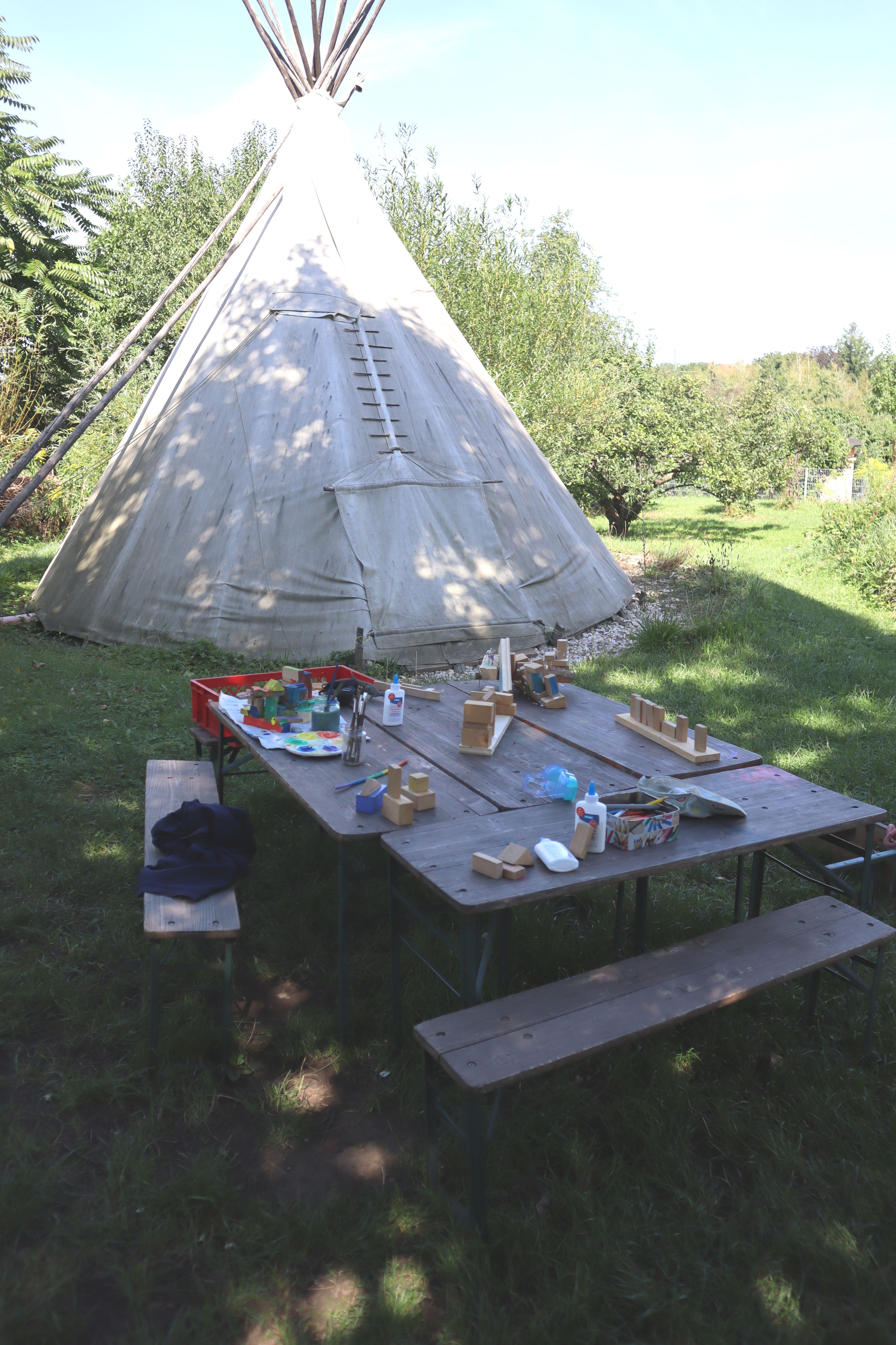 Gedeckter Holztisch und Tipi im Hintergrund