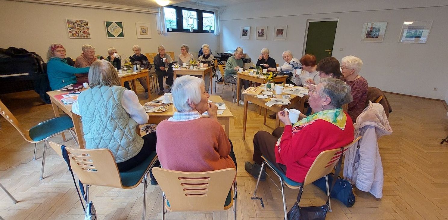 Viele Frauen sitzen im Kreis an Tischen